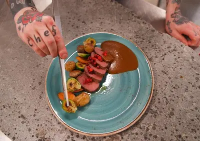 a person holding a fork and a plate of food at Oset Fjellhotell in Gol