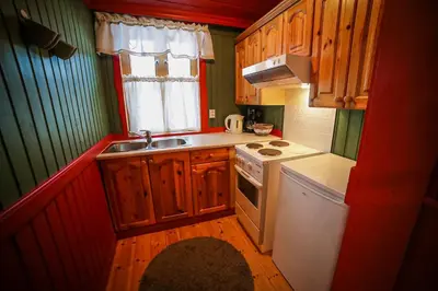 a kitchen with wooden cabinets and a white stove top oven at Vesterland Feriepark Hytter, hotell og leikeland in Sogndal