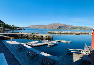 a dock with a boat in a body of water at Bakkevik Brygge in Kalvåg