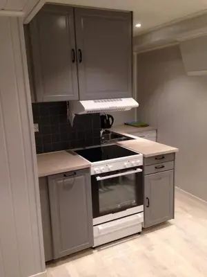 a kitchen with gray cabinets and a stove top oven at Bakkevik Brygge in Kalvåg