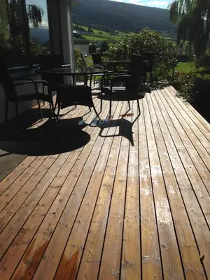a wooden deck with a table and chairs on it at Innvik Fjordhotell in Innvik