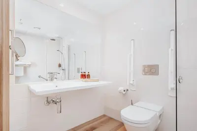 a white bathroom with a toilet and a sink at Wood Hotel by Frich's in Brumunddalen