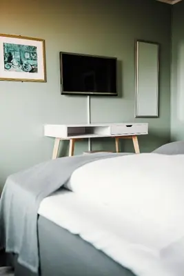 a bedroom with two beds and a tv on the wall at Vågslidtun Hotel in Vågsli