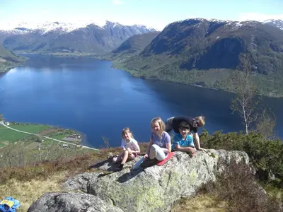 three children sitting on a rock overlooking a lake at Jølsterlia Hyttetun in Årdal