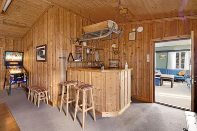 a kitchen with wooden walls and a counter with stools at Hardanger Guesthouse in Ulvik