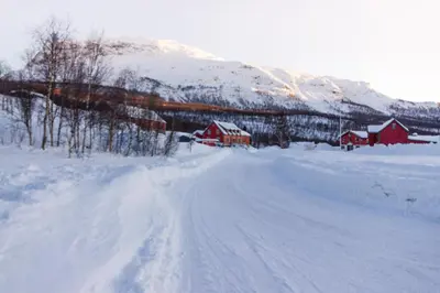 a snow covered road with houses and a mountain at Maristova apartment 109 in Filefjell