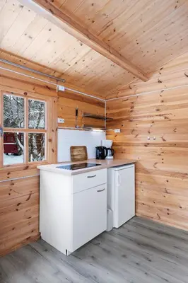 a kitchen with white appliances in a wooden cabin at Birkelund camping in Geilo