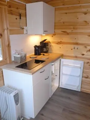 a kitchen with white cabinets and wooden walls at Birkelund camping in Geilo