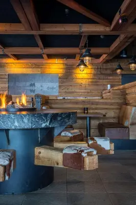 a restaurant with a fireplace in a room with logs at Skistar Lodge Trysil in Trysil