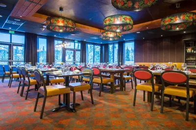 a dining room with tables and chairs and chandeliers at Skistar Lodge Trysil in Trysil