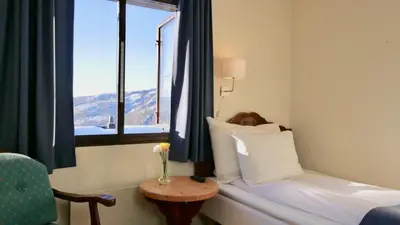 a hotel room with a bed and a window at Rondane Høyfjellshotell in Mysusæter