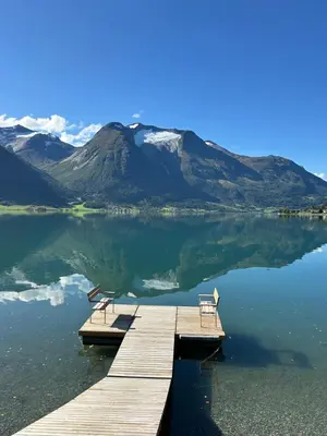 a dock with two benches on a lake with a mountain at Vollsnes Feriehus in Hjelle