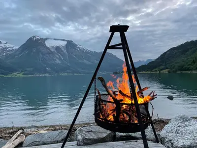 a fire in a basket next to a body of water at Vollsnes Feriehus in Hjelle