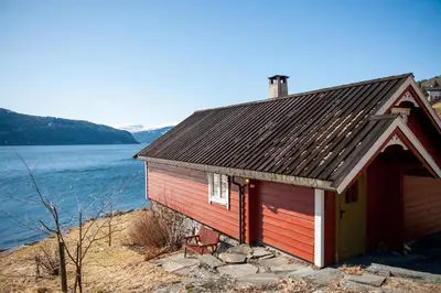 a red building next to a body of water at Bodvarstova in Stryn