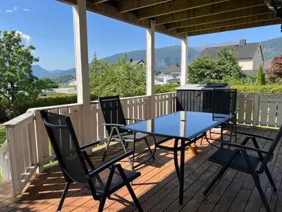 a table and chairs on a deck with a grill at Åndalsnes gustehouse in Åndalsnes