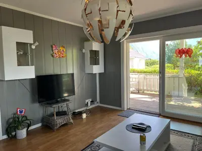 a living room with a flat screen tv and a chandelier at Åndalsnes gustehouse in Åndalsnes