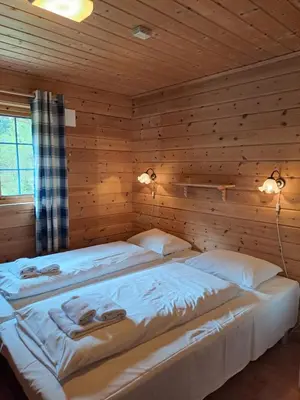 two beds in a room with a wooden wall at Stardalen Hyttegrend in Klakegg