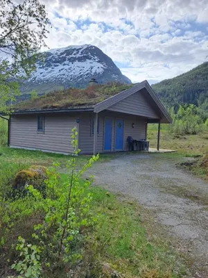 a small house with a snow covered mountain in the background at Stardalen Hyttegrend in Klakegg