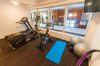 a gym with two tread machines and a window at Dolmsundet Hotell Hitra in Melandsjøen