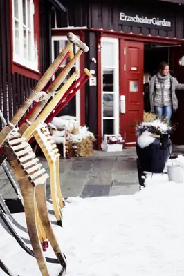 a wooden bench sitting in the snow in front of a building at Erzscheidergaarden Hotell in Røros