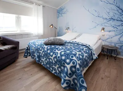 a bedroom with a bed with a blue and white blanket at Erzscheidergaarden Hotell in Røros