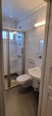 a bathroom with a shower and a toilet and a sink at Erzscheidergaarden Hotell in Røros