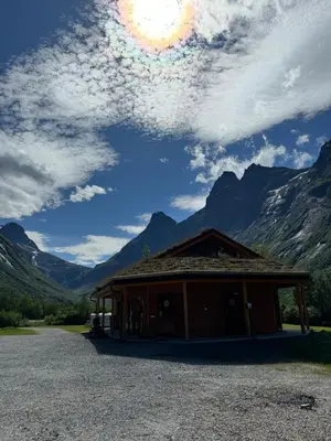 a building with mountains in the background at Trollstigen Camping and Gjestegård in Åndalsnes