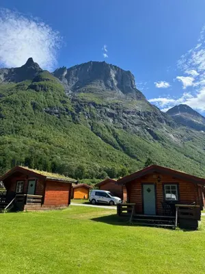a mountain with a car parked in front of houses at Trollstigen Camping and Gjestegård in Åndalsnes