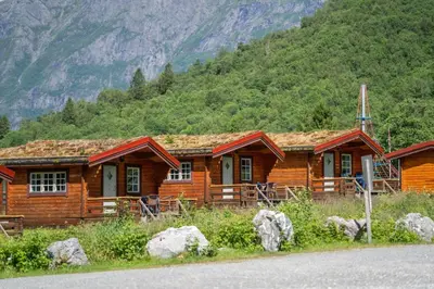 a log cabin with mountains in the background at Trollstigen Camping and Gjestegård in Åndalsnes