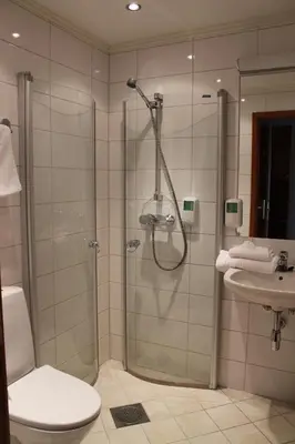 a bathroom with a shower and a toilet and a sink at Alver Hotel in Alversund