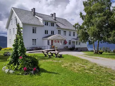a large white house with benches in front of it at Granum Gård in Fluberg