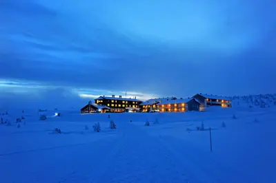 a large building in the snow at night at Pellestova Hotell Hafjell in Hafjell