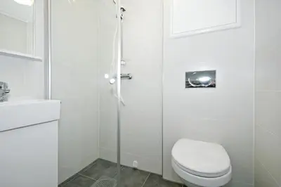 a white bathroom with a toilet and a shower at Vossestrand Hotel and Apartments in Myrkdalen