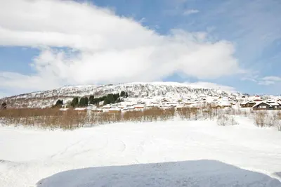 a snow covered mountain with a village in the background at Vossestrand Hotel and Apartments in Myrkdalen