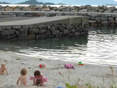 three children playing in the sand on the beach at 6 person holiday home in Åram-By Traum in Sandvik