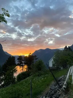a sunset in the mountains with a house on a hill at Kvam - Stegastein in Aurland