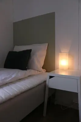 a bed with a lamp next to a side table at Valldal Gjestgiveri in Valldal