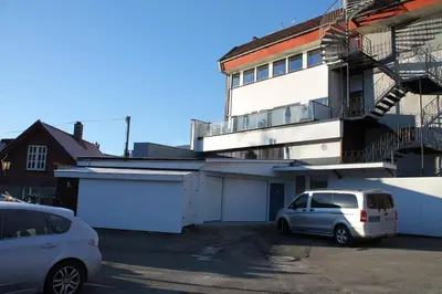 two cars parked in a parking lot in front of a building at Kløver Hotel in Sauda