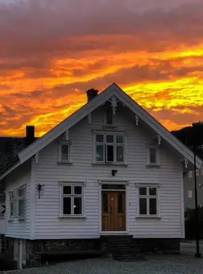a white house with a sunset in the background at Kløver Hotel in Sauda