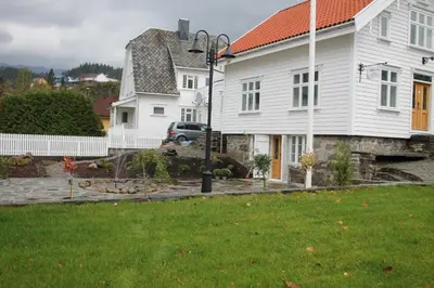 a white house with a yard and a driveway at Kløver Hotel in Sauda