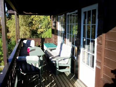 a porch with two chairs and a table on a house at Hogstul Hytter - Knatten - 3 Bedroom Cottage in Tuddal