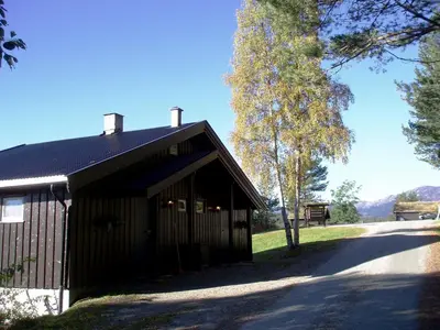 a black building with a tree next to a road at Hogstul Hytter - Apartment South in Tuddal
