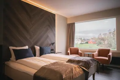 a bedroom with a large bed and a large window at Rosendal Fjordhotel in Rosendal