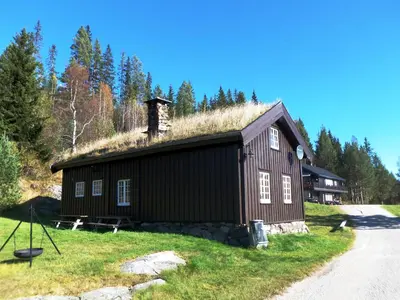 a barn with a grass roof on a field at Hogstul Hytter - Gamlestua in Tuddal