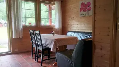 a dining room with a table and chairs and windows at Folven Adventure Camp in Hjelle