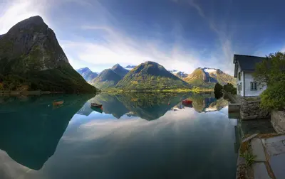 a view of a lake with a house and mountains at Folven Adventure Camp in Hjelle