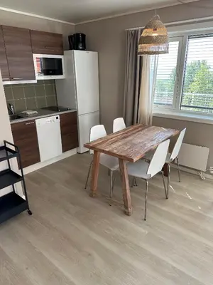 a kitchen with a wooden table and white chairs at Hedmarktoppen in Hamar