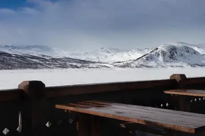 a view of a snowy mountain range from a bench at Storestølen Fjellhotell in Hovet