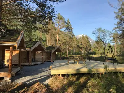 a cabin with a picnic table and a swing at Camp Dronningkrona in Ålvundeid