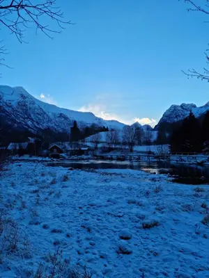 a snow covered field with mountains in the background at Naustvoll in Olden
